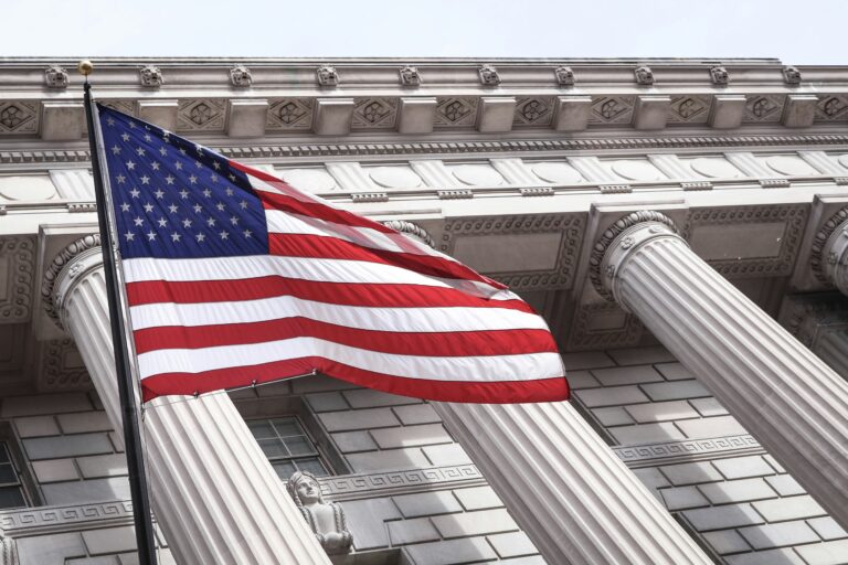 American flag displayed before a building with classical columns, symbolizing constitutional principles, civic responsibility, foundational values, and organizational strength.