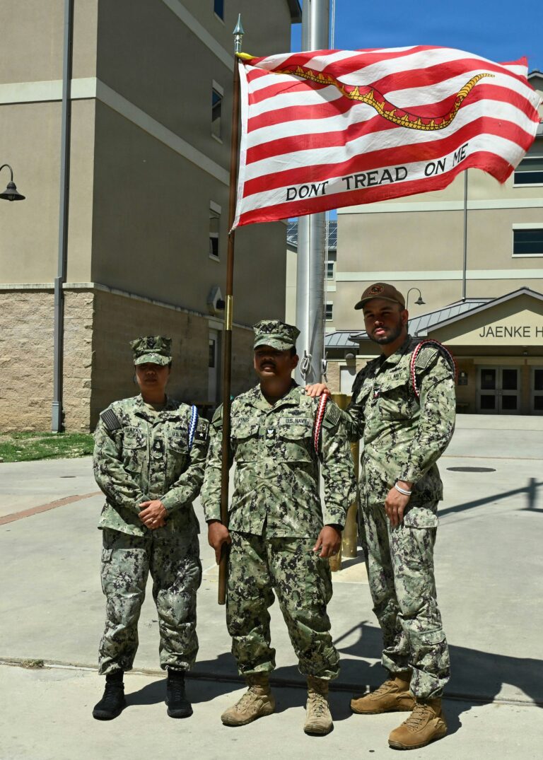 Members standing beside a historical Gadsden-style flag representing constitutional heritage, organizational tradition, and civic preparedness within the 55th Light Foot framework.