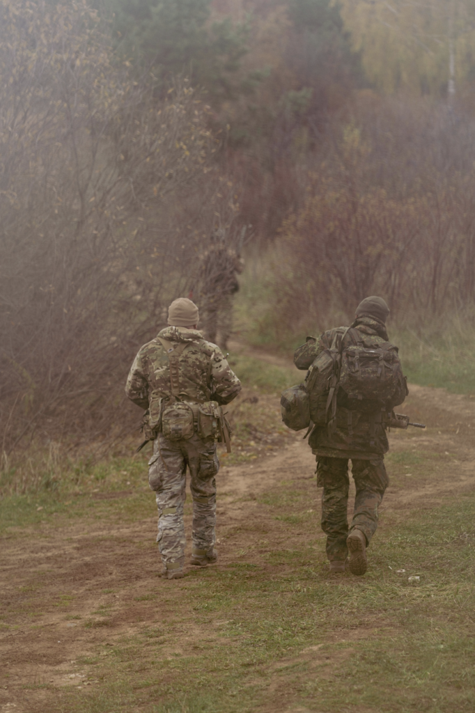 55th Light Foot Battalion members conduct a field training exercise on a wooded trail, practicing movement, navigation, and team coordination in a realistic outdoor environment.